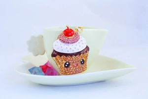 Close-up of a sparkling rhinestone cupcake keychain hanging on a white coffee cup