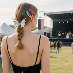 Silver metal bat wing hair claw and colorful clips worn on a braided hairstyle outdoors