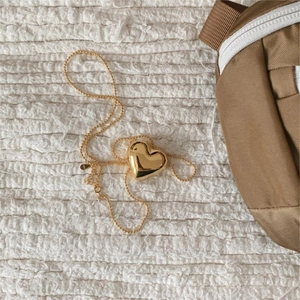 Detail of a polished gold heart pendant with S925 engraving on a fine bead chain