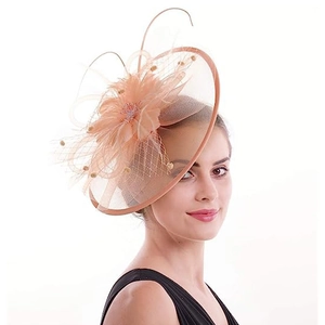 Detail of elegant orange fascinator hat with delicate mesh veil and feather floral accents