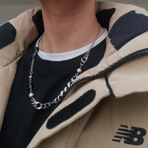 Silver OT buckle chain necklace with black beads and pearls worn by a model on a beige jacket