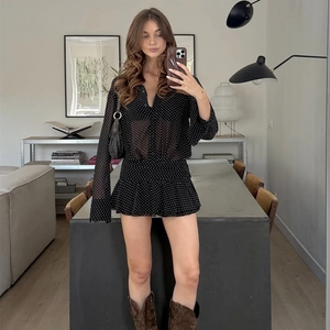 Dettagli di un vestito nero a pois con cuciture in chiffon e colletto polo alla moda
