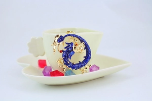 Detail of a blue enamel dragon pendant with a pearl in a decorative ceramic flower cup