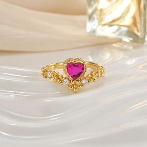 Macro detail of crown-shaped gold ring with pink heart stone and floral pave accents