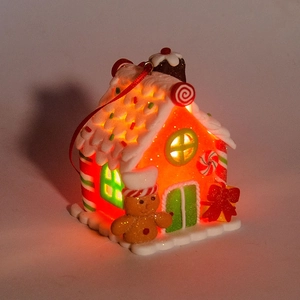 Macro view of a lit gingerbread house ornament with a red bow and a gingerbread man