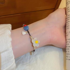 Détail d'un bracelet perlé avec fleur et cœur au poignet dans une ambiance chaleureuse