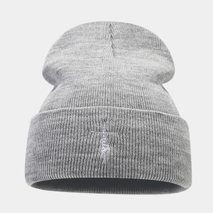 Detailed view of white embroidery on dark grey ribbed knit beanie with warm texture
