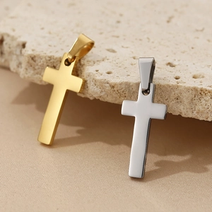 Polished gold and silver stainless steel cross pendants on a natural stone surface