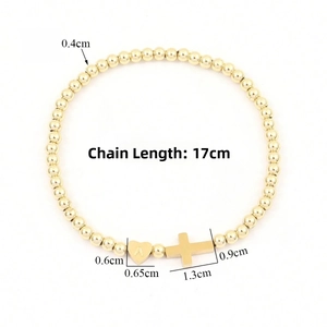 Close-up of gold beaded bracelet with letter A heart charm and small cross pendant