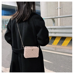 Quilted beige jelly bag with chain strap shown on model in urban street setting