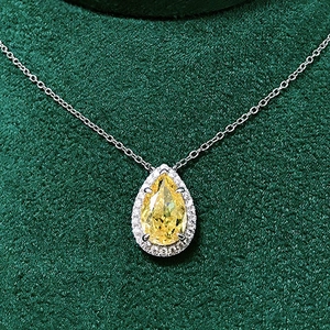Detail of pear-cut yellow zircon pendant with halo diamonds on a silver chain