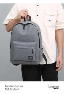 Detailed view of grey heather fabric texture and front zipper pocket on a travel backpack