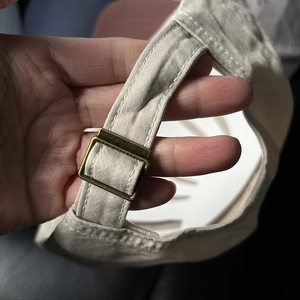 Close-up of adjustable copper buckle and durable twill fabric on beige baseball cap
