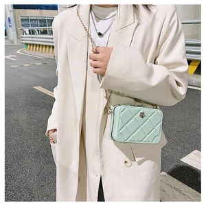 Chic mint green PVC jelly bag with quilted pattern and gold chain strap on a stylish model