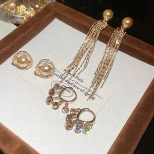 Detailed close-up of gold tassel earrings with pearls and zircons in a jewelry box