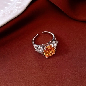 Close-up of square orange zircon ring with silver prong setting on red velvet