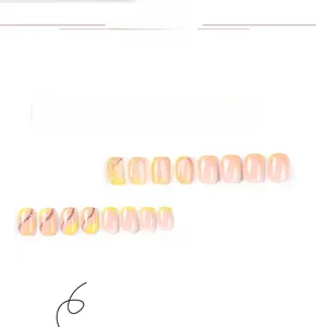 Close-up of short yellow French press-on nails with glitter accents and wave patterns