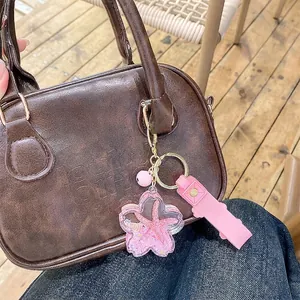 Pink marine animal liquid quicksand keychain with stars and bells on a handbag