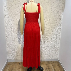 Detail of red tiered maxi dress featuring tie straps and a ruched elastic back design