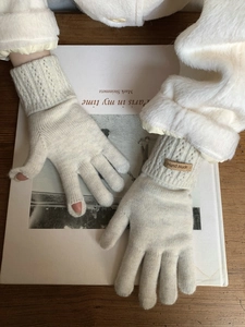 Detail of knitted cashmere gloves featuring touch-screen opening and Hand Made leather label