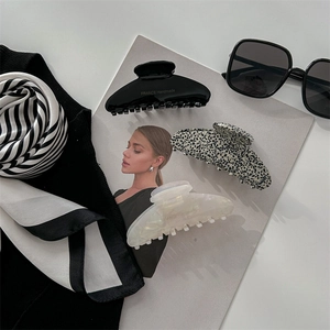 French style acetate hair claws in black, tortoiseshell, and white on a magazine background