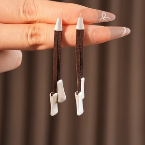 Detail view of brown suede cord earrings with irregular silver metal pieces being held