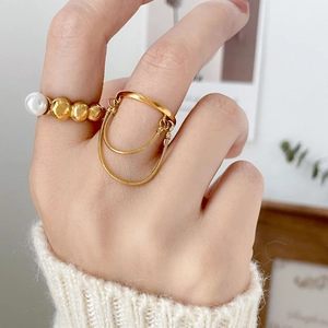 Detailed view of gold pearl bead ring and double-layered snake chain tassel ring jewelry
