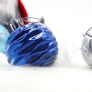 Blue wave-textured Christmas ball ornament with silver string on white plush surface