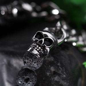 Macro detail of silver skull charm and black lava stone beads with porous texture