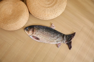 Detailed view of realistic fish plush pillow showing gray scale texture on wood floor