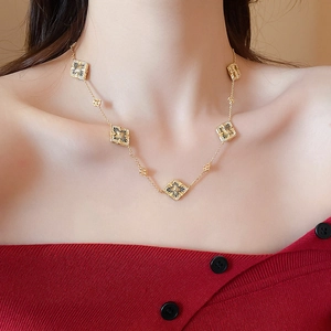 Detail of gold plated necklace with five black geometric flower pendants on a model