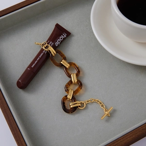 Detail of amber resin links and gold stainless steel chain with T-bar toggle closure