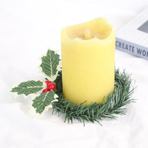 Detail of a pillar candle centered on a green holly wreath base over white linen cloth