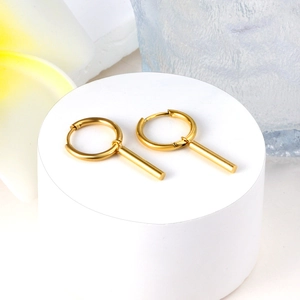 Golden chain link earrings with cylindrical drop on minimalist white display stand