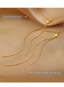 Detailed macro shot of long golden tassel earrings with fine snake chain textures
