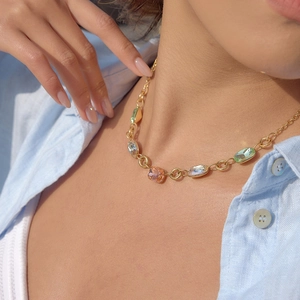 Primo piano della collana a catena dorata con cristalli ovali colorati su un modello