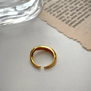 Artistic display of minimalist gold open ring on vintage paper with glass decor