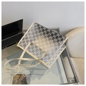 Detail of transparent white tote bag featuring black M-letter pattern on a desk