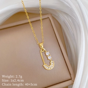 Detailed close-up of a golden pin-shaped pendant with zircons on an elegant jewelry box