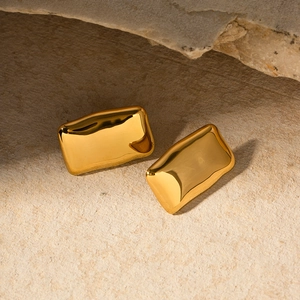 Detailed view of 18K gold rectangular lava texture earrings on a natural stone base