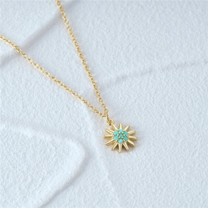 Detailed close-up of a gold sunflower pendant necklace featuring inset turquoise gemstones
