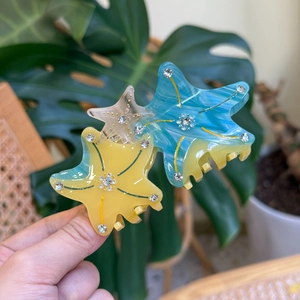 Eleganter Haarklammer Seestern mit blauem Marmormuster und Strass auf tropischem Blatt