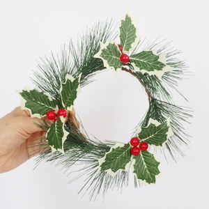 Close-up of Christmas candle ring featuring green pine needles, holly leaves and red berries