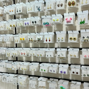 Various stylish alloy stud earrings in assorted colors and shapes on a display rack