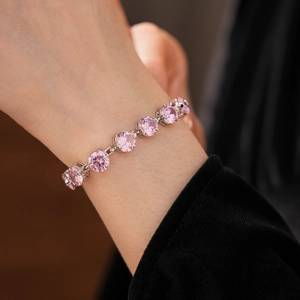 Detailed close-up of a pink zircon silver bracelet worn on a woman's wrist