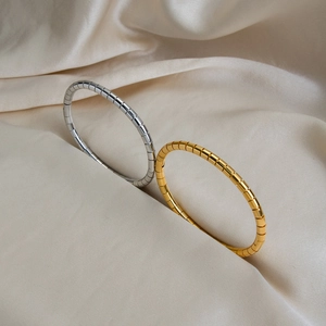 Minimalist bamboo joint gold and silver stainless steel bracelets on white satin fabric