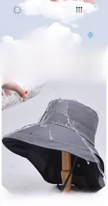 Gros plan de gouttes d'eau glissant sur le chapeau de soleil gris foncé imperméable