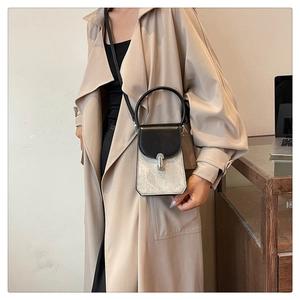 Silver and black mini crossbody phone bag shown on a model wearing a beige trench coat