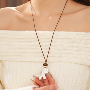 Détail du pendentif licorne argentée avec perle marron sur un cordon tressé marron
