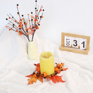 Macro detail of autumn pumpkin berry candle ring with orange maple leaves and yellow candle
